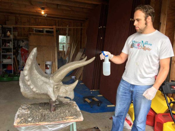 Spraying the ferrocement triceratops head with water.